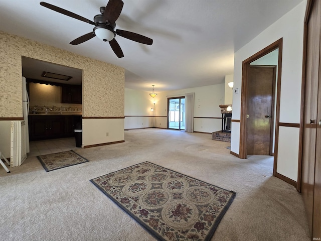 interior space with baseboards, wallpapered walls, a ceiling fan, and light colored carpet