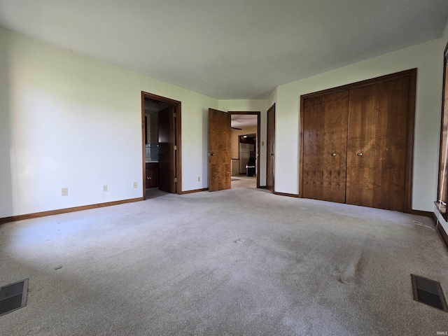 unfurnished bedroom featuring baseboards, visible vents, light carpet, and a closet