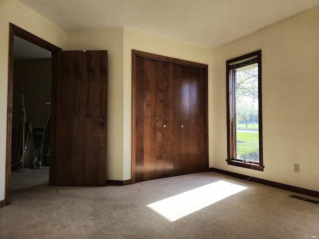 unfurnished bedroom with a closet, visible vents, carpet, and baseboards