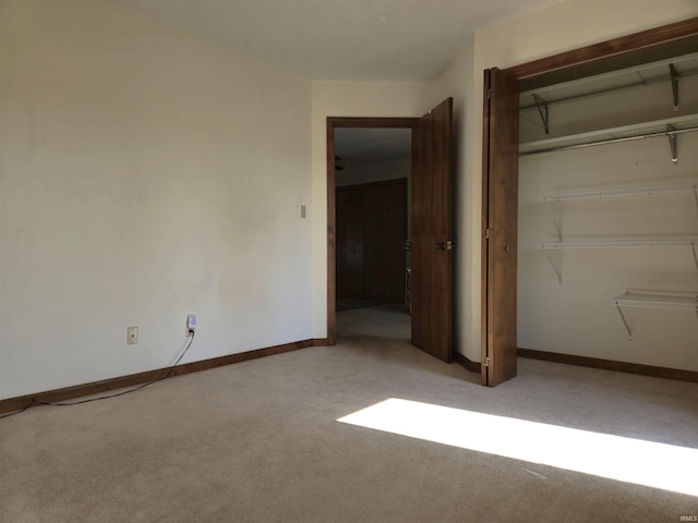 unfurnished bedroom featuring a closet, baseboards, and light carpet