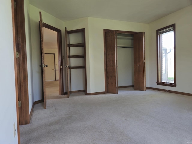 unfurnished bedroom with a closet, light colored carpet, and baseboards