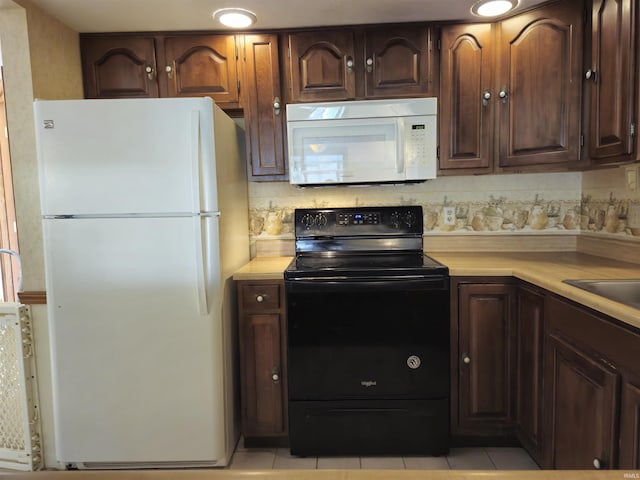 kitchen with light tile patterned floors, tasteful backsplash, light countertops, dark brown cabinetry, and white appliances