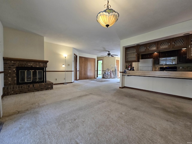 unfurnished living room featuring ceiling fan, baseboards, carpet floors, and a fireplace