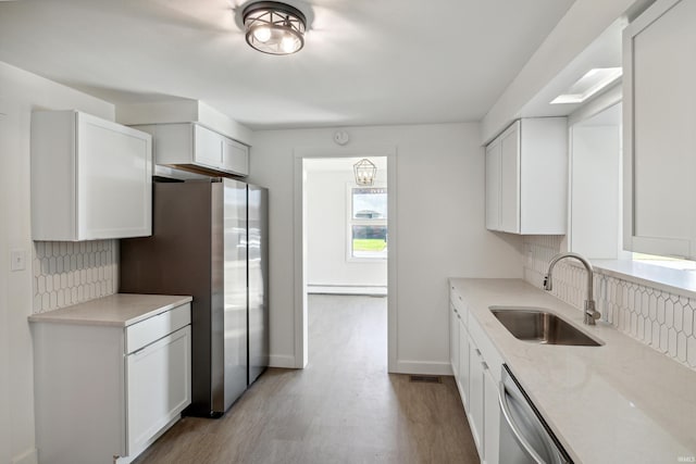 kitchen with light wood finished floors, a sink, backsplash, and stainless steel appliances