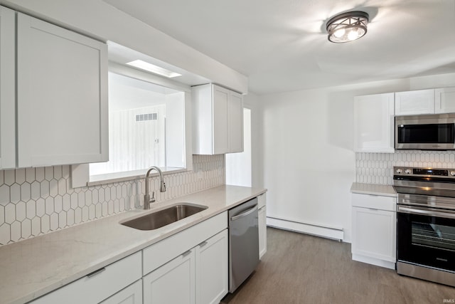 kitchen with white cabinetry, decorative backsplash, a sink, a baseboard radiator, and stainless steel appliances