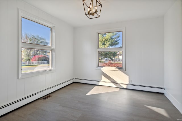 empty room with wood finished floors, a wealth of natural light, and a notable chandelier