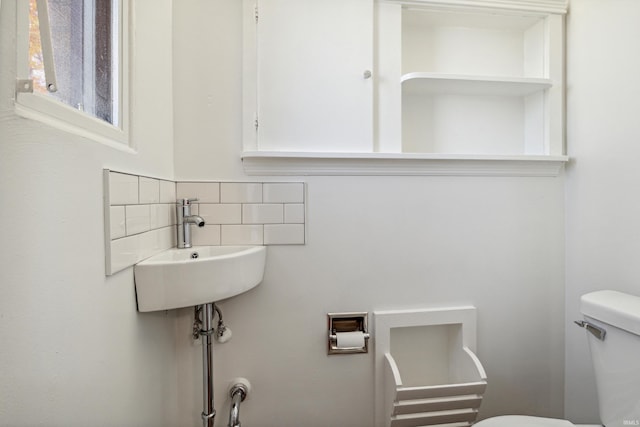 half bath featuring toilet, a sink, and tasteful backsplash