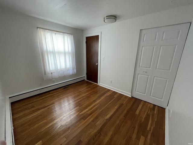 unfurnished bedroom with dark wood-style flooring, baseboards, and a baseboard radiator
