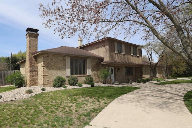 view of front of house featuring fence, a chimney, a front yard, and brick siding