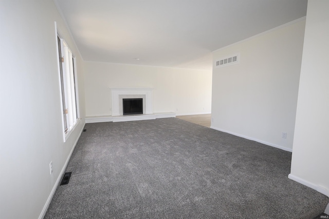unfurnished living room with carpet, visible vents, a fireplace with raised hearth, and baseboards
