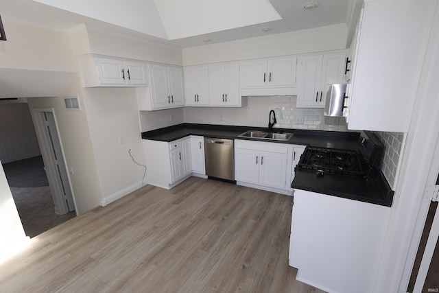 kitchen featuring tasteful backsplash, dark countertops, dishwasher, a sink, and visible vents