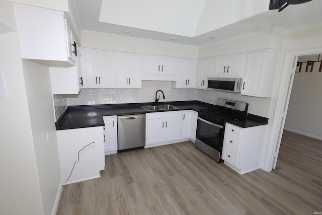 kitchen with dark countertops, stainless steel appliances, light wood-style flooring, and a sink