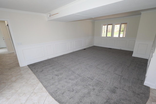 spare room featuring wainscoting, crown molding, and a decorative wall