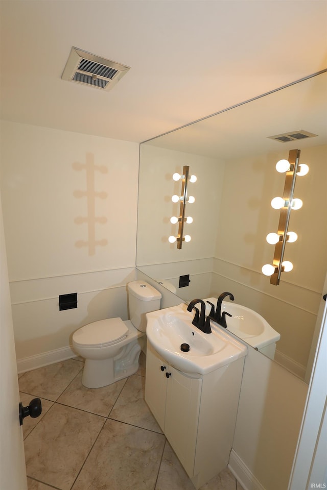 half bath with toilet, visible vents, vanity, and tile patterned flooring