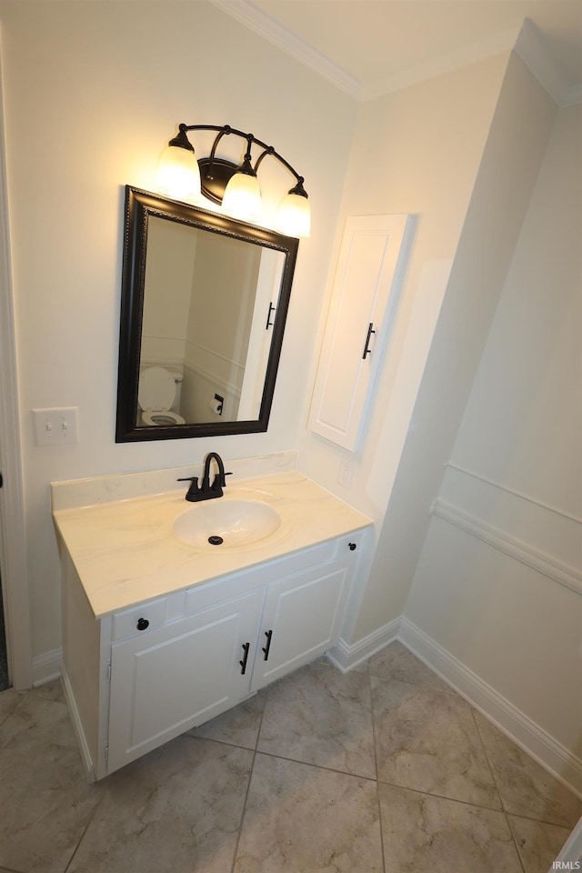 bathroom featuring baseboards, ornamental molding, and vanity