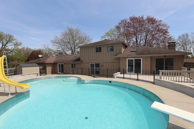view of pool featuring a patio area, a diving board, a fenced in pool, a water slide, and fence