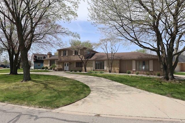 view of front of house featuring a front lawn, stone siding, board and batten siding, and curved driveway
