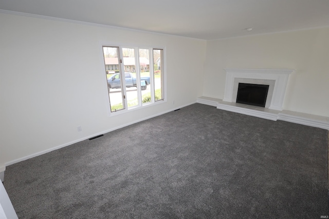 unfurnished living room with dark carpet, visible vents, a fireplace with raised hearth, and ornamental molding