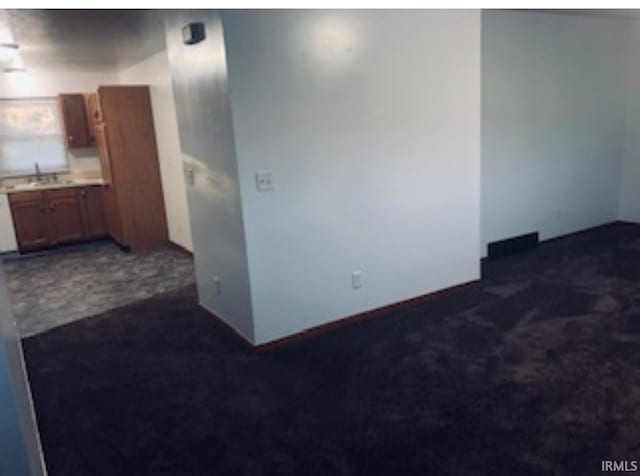 spare room with a sink and dark colored carpet