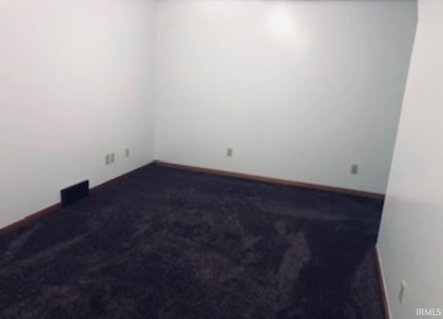 spare room with baseboards and dark colored carpet