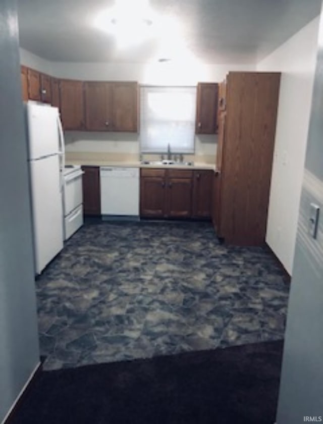 kitchen featuring white appliances, brown cabinets, a sink, and light countertops