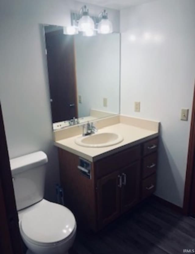 half bathroom featuring vanity, toilet, and wood finished floors