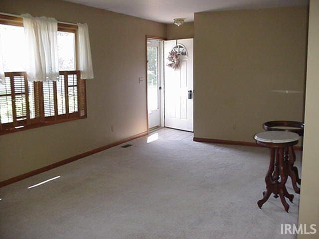 foyer entrance with baseboards and carpet