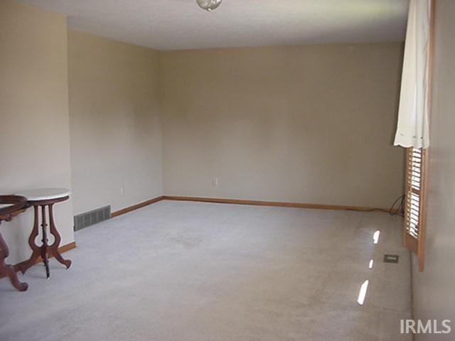 carpeted empty room featuring baseboards and visible vents