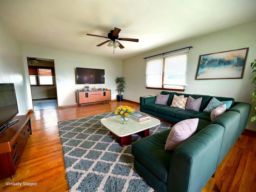 living area featuring wood finished floors, a ceiling fan, and baseboards