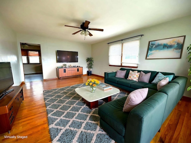 living area featuring wood finished floors, a ceiling fan, and baseboards