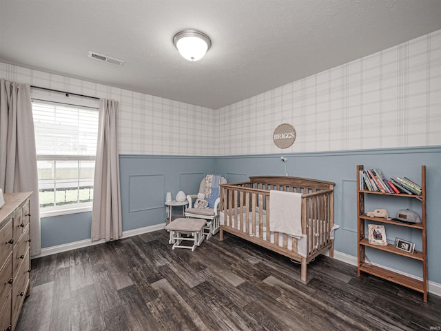 bedroom with dark wood-style flooring, visible vents, wallpapered walls, and baseboards