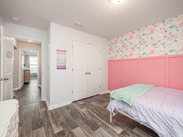 bedroom featuring wallpapered walls, a closet, a wainscoted wall, visible vents, and dark wood-type flooring