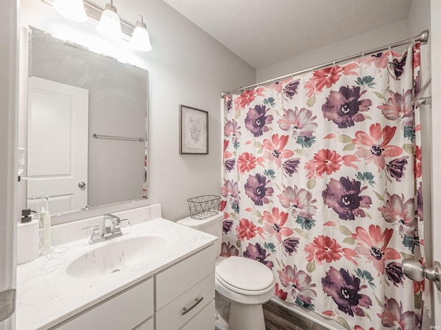 full bathroom with a textured ceiling, curtained shower, toilet, wood finished floors, and vanity