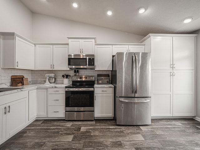 kitchen featuring white cabinetry, backsplash, appliances with stainless steel finishes, and lofted ceiling