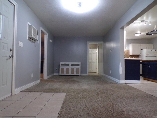 interior space with baseboards, light tile patterned floors, a wall unit AC, and light carpet