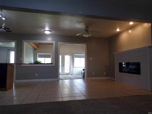 unfurnished living room with tile patterned floors, baseboards, ceiling fan, and a fireplace