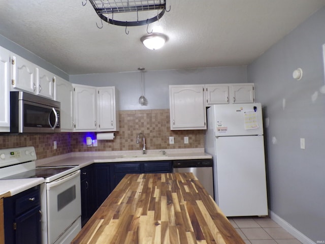 kitchen with white cabinetry, a sink, appliances with stainless steel finishes, blue cabinets, and butcher block counters