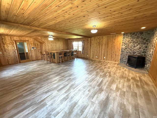 unfurnished living room with a wood stove, wood finished floors, wood walls, and wooden ceiling