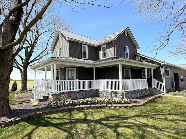 country-style home with covered porch, metal roof, and a front yard