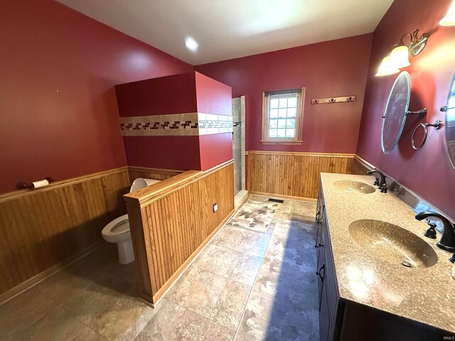 bathroom with a sink, a wainscoted wall, toilet, and wood walls
