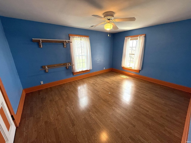 spare room with baseboards, ceiling fan, and wood finished floors