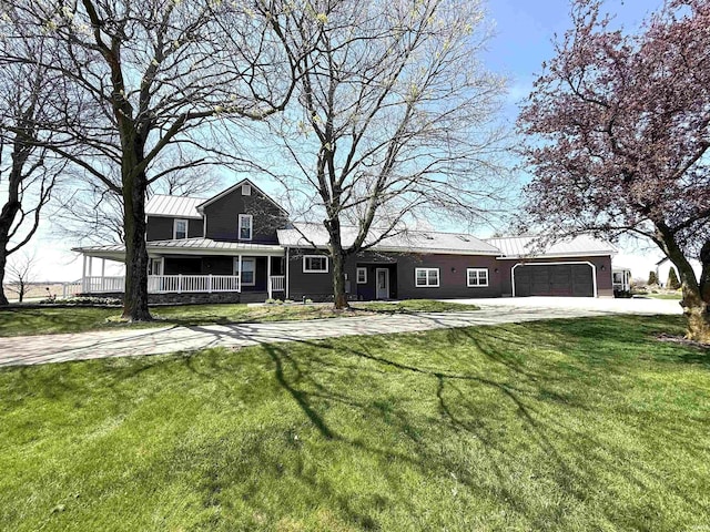 view of front of property featuring covered porch, a standing seam roof, metal roof, a garage, and a front lawn