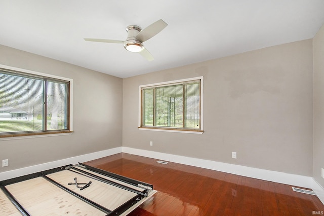 empty room with baseboards, a wealth of natural light, hardwood / wood-style floors, and visible vents
