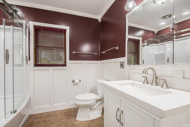 bathroom featuring ornamental molding, a decorative wall, a wainscoted wall, and toilet