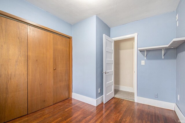 unfurnished bedroom with a closet, baseboards, and wood finished floors