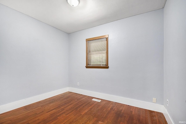unfurnished room with baseboards, dark wood-type flooring, and visible vents