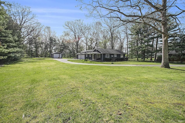 view of yard with a detached garage, driveway, and an outbuilding
