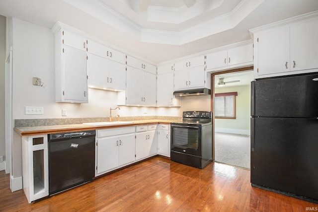 kitchen with crown molding, hardwood / wood-style flooring, a sink, black appliances, and under cabinet range hood