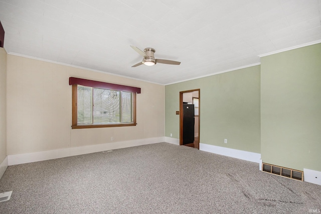 carpeted spare room with crown molding, a ceiling fan, baseboards, and visible vents