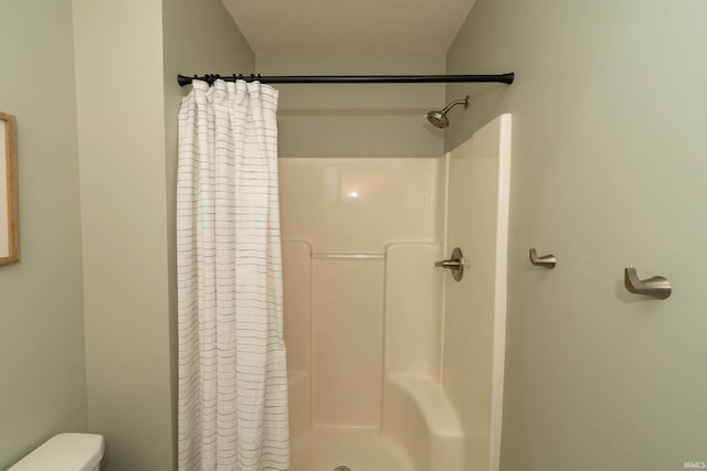 bathroom with a shower with shower curtain and toilet